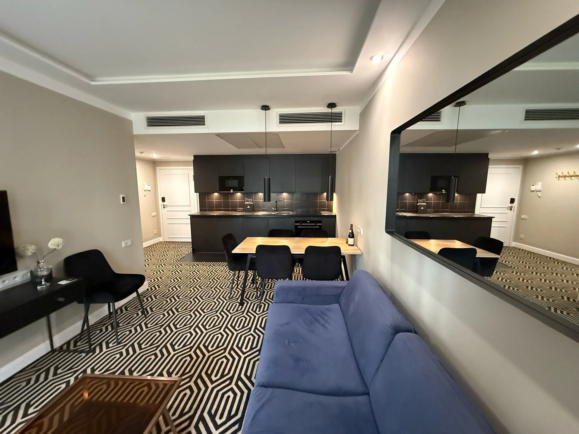 Offener Wohn-, Ess- und Küchenbereich des Apartments mit blauem Sofa